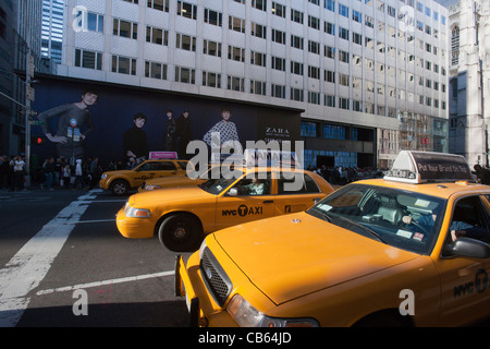 Taxis warten an einer Ampel auf der Fifth Avenue vor einem Bau-Schuppen zur Förderung einer neuen Zara-Filiale in New York Stockfoto