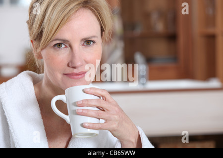 Blonde Frau im Morgenmantel Kaffee trinken Stockfoto