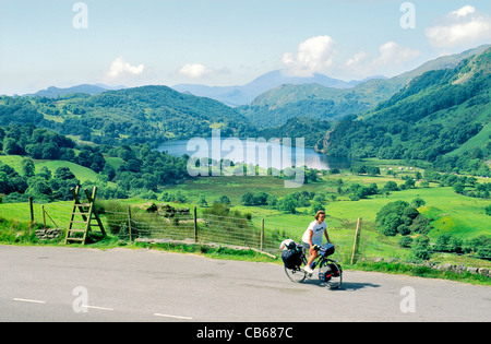 Frau Touring Radfahrer auf dem Fahrrad unterwegs über Llyn Gwynant See von Nant Cynnyd in Snowdonia National Park, Nord-Wales, UK Stockfoto