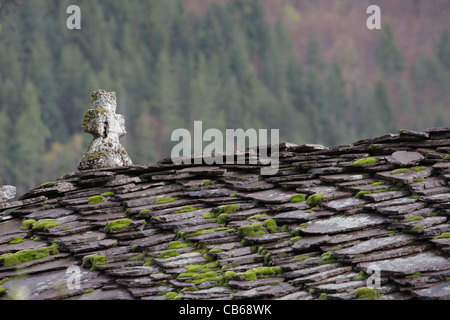 Schieferdach einer orthodoxen Kirche Kreuz. Steinfliesen mit Moos und Flechten auf Dach. Traditionelle Architektur in Bulgarien. Stockfoto