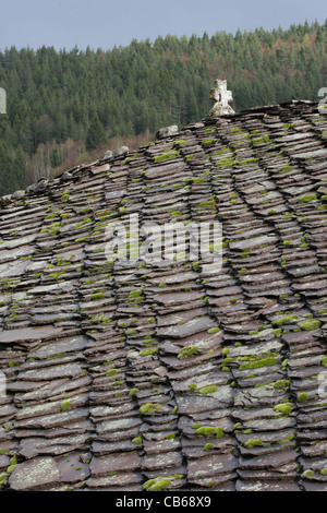 Schieferdach einer orthodoxen Kirche mit Kreuz. Steinfliesen mit Moos und Flechten auf Dach. Traditionelle Architektur in Bulgarien. Stockfoto