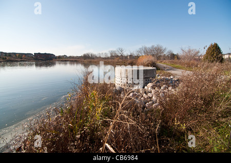 Eine perforierte Betonrohr Bestandteil ein Regenwasser-Management-System in einem vorstädtischen Teich. Stockfoto