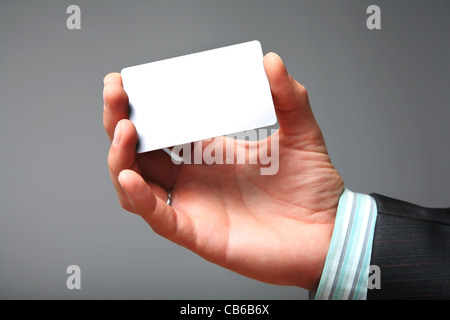 Leere Visitenkarte in der Hand des Kaufmanns. Grau hinterlegt. Stockfoto