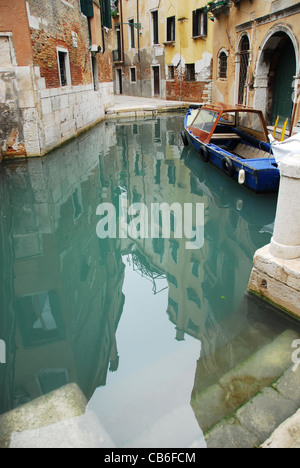 Boot vor Anker vor einigen Häusern spiegelt sich im Wasser in der Altstadt von Venedig Stockfoto