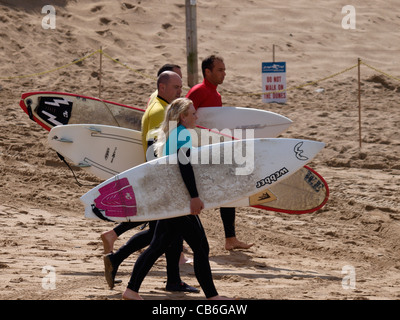 Gruppe von Surfern, die einem Strandspaziergang, Fistral Strand, Newquay, Cornwall, UK Stockfoto