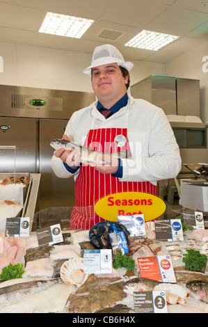 Mann hält eine Regenbogenforelle an der Fischtheke in einem Tesco Speicher Stockfoto