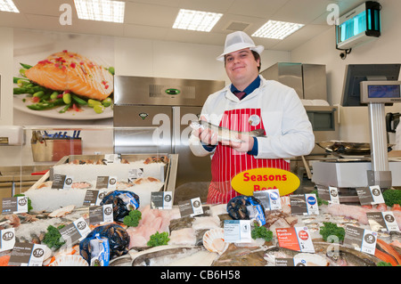 Mann hält eine Regenbogenforelle an der Fischtheke in einem Tesco Speicher Stockfoto