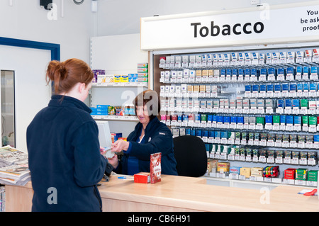 Frau wird in einem Tesco Tankstelle serviert. Stockfoto