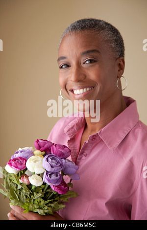Afroamerikanische Frau hält Blumenstrauss Lächeln auf den Lippen. Stockfoto