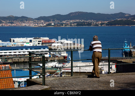 Mann schaut Blick über Hafen und Ria de Vigo, Dorf von Cangas in Hintergrund, Vigo, Galizien, Spanien Stockfoto