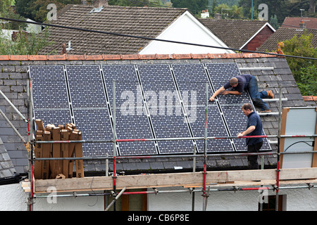 Zwei Männer, die Montage von Sonnenkollektoren zu Haus auf dem Dach im Dorf Wales UK Stockfoto