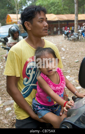 Kambodschanische Mann mit seiner Tochter sitzt auf einem Moped bei einem Dorffest, kambodschanischen Neujahr (Chaul Chnam Thmey), Bakong Dorf, Siem Reap, Kambodscha Stockfoto