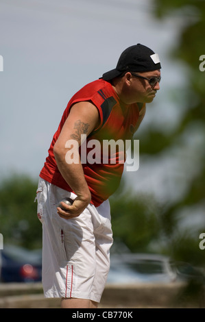 Ein Konkurrent in der traditionellen französischen Spiel Boule oder Boccia konzentriert sich hart, Kugel in der hand, auf seine nächste Wurf. Stockfoto