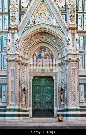 Touristen sitzen neben den massiven Vordertüren nach Dom - Santa Maria del Fiore, Florenz Toskana Italien Stockfoto