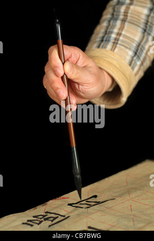 Ein Alter Mann ist mit einem Pinsel-Stift in seiner Freizeit Kalligraphie üben Stockfoto