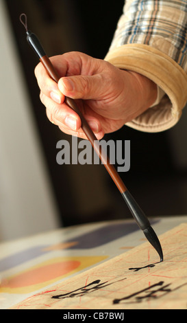 Ein Alter Mann ist mit einem Pinsel-Stift in seiner Freizeit Kalligraphie üben Stockfoto