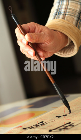 Ein Alter Mann ist mit einem Pinsel-Stift in seiner Freizeit Kalligraphie üben Stockfoto