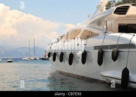 Große weiße Yacht ankern in der Bucht von Portofino gegen kleine Yachten und Motorboote in Ligurien, Norditalien. Stockfoto