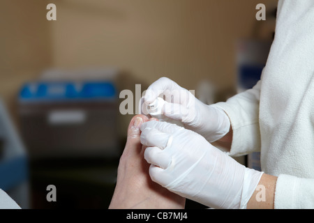 Eine Fußpflegerin bearbeitet die Zehennägel mit Maniküre Öl Stockfoto