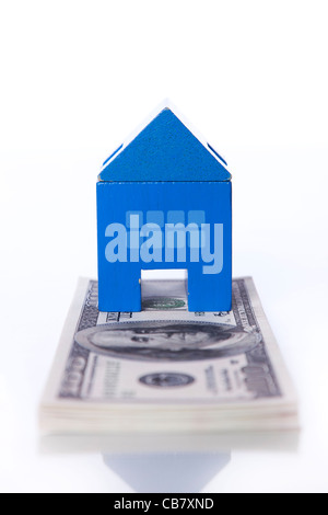 blaue Spielzeug Haus über eine Menge von Dollarnoten isoliert auf weiss (Tiefenschärfe) Stockfoto