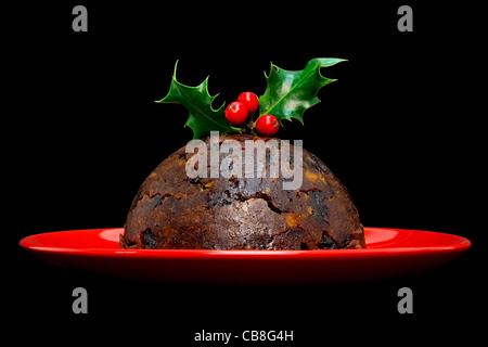 Foto von einem Christmas Pudding mit Holly an der Spitze auf schwarzem Hintergrund isoliert. Stockfoto