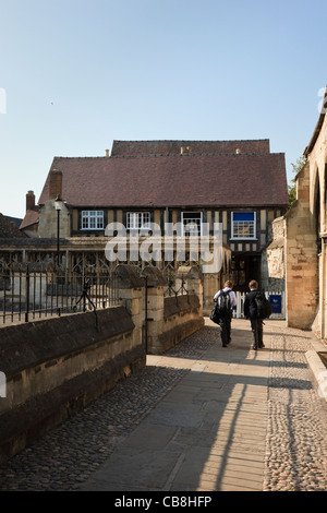 Schüler, die das kleine Tuchmacherhaus der Königsschule auf dem Domplatz betreten. Gloucester Gloucestershire England Großbritannien Stockfoto