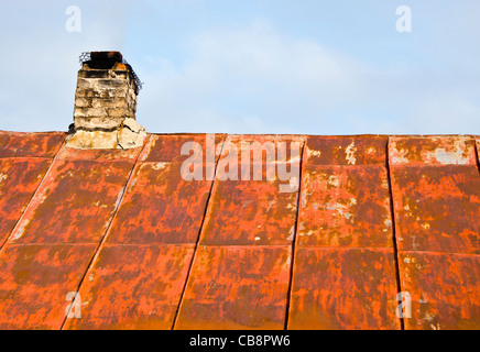Dach aus rostigen Zinn und marode Ziegel-Schornstein eines alten verlassenen Landhauses. Stockfoto