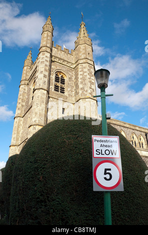 Ein 5 km/h Höchstgeschwindigkeit Verkehrsschild gegen eine abgeschnittene Taxushecke, St. Mary Parish Church Tower Beaconsfield im Hintergrund Stockfoto