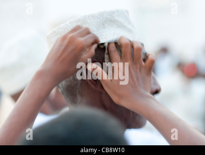 Menschliche Mädchen Hand setzen Banknote In Kofia getragen von Senior woman, Maulidi, Lamu, Kenia Stockfoto