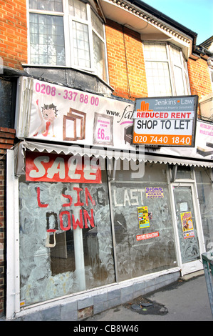 Ein leerer Shop in eine Vorstadt London Hauptstraße mit "Schließung Verkauf" auf einem Fenster und ein Agenten-Board bietet Miete reduziert. Stockfoto