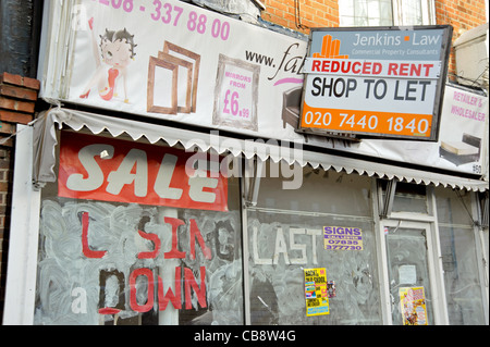 Ein leerer Shop in eine Vorstadt London Hauptstraße mit "Schließung Verkauf" auf einem Fenster und ein Agenten-Board bietet Miete reduziert. Stockfoto