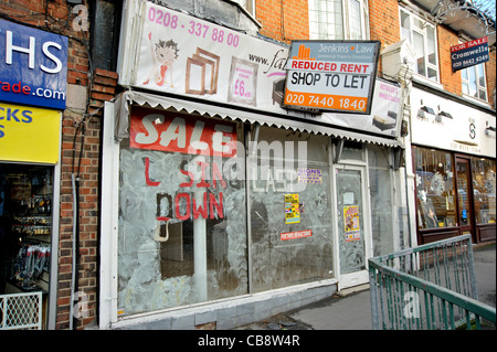 Ein leerer Shop in eine Vorstadt London Hauptstraße mit "Schließung Verkauf" auf einem Fenster und ein Agenten-Board bietet Miete reduziert. Stockfoto