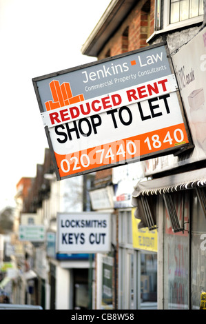 Ein leerer Shop in eine Vorstadt London Hauptstraße mit "Schließung Verkauf" auf einem Fenster und ein Agenten-Board bietet Miete reduziert. Stockfoto