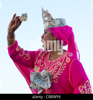 Junge Frau gekleidet in rosa Anzug mit Baknotes Hut wegwerfen, Maulidi, Lamu, Kenia Stockfoto