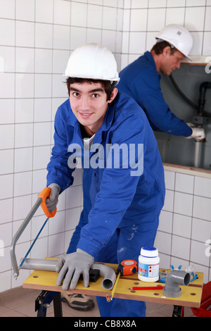 Junge Klempner schneiden Kunststoffrohr Stockfoto