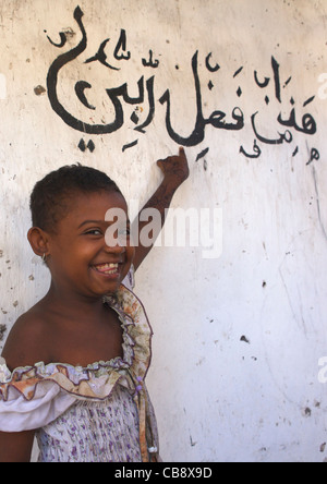 Kleines Mädchen mit arabischer Inschrift an einer Wand, Lamu, Kenia Stockfoto