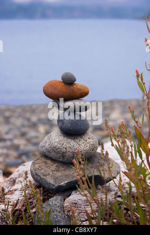 Cairn thront auf einem felsigen Strand.  Beschriftung-Platz an der Spitze. Stockfoto