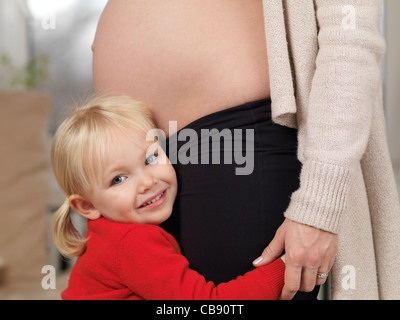 Schwangere Mutter und ihre glückliche 3 jährige kleine Tochter zusammen Stockfoto