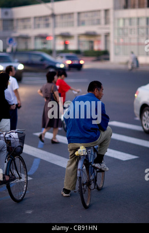 Radfahrer und Fußgänger überqueren an einem Zebrastreifen in ein beschäftigt kommerziellen Bezirk von Peking, China. Stockfoto