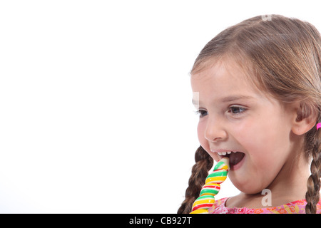 kleine Mädchen essen ein Bonbon sah amüsiert und schelmischen Stockfoto