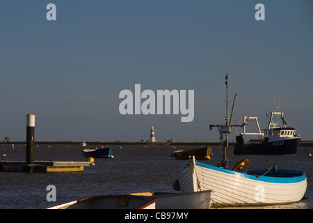 Boote am Orford Quay in Suffolk, England, mit Orford Ness Leuchtturm in der Ferne Stockfoto