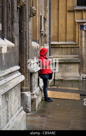 Junge Frau, SMS auf Handy, in der alten Schule Viereck der Bodleian Library, University of Oxford, Oxford, England, UK Stockfoto