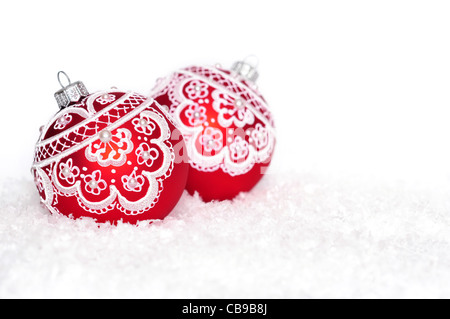 Rote Weihnachtskugeln mit Muster auf Schnee auf weißem Hintergrund Stockfoto