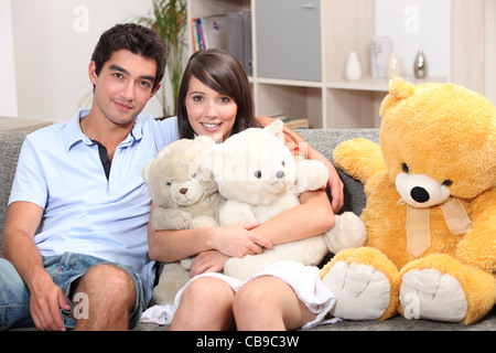 Paar saß auf der Couch mit Kuscheltieren Stockfoto