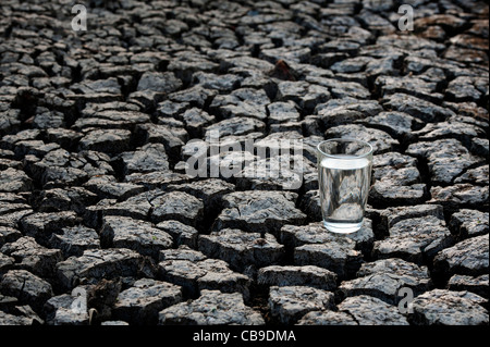 Glas Wasser auf die trockene Rissige Erde. Indien Stockfoto