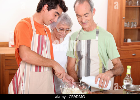 ein 20 Jahre alten Jungen und 65 Jahre alter Mann und eine Frau gemeinsam Kuchen machen Stockfoto