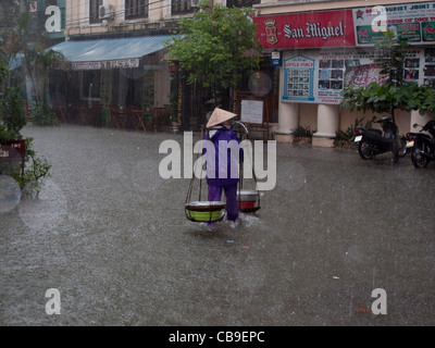 Frau Straßenhändler gefangen im Monsun-Regen-Regen in einer Stadtstraße in Hue, Vietnam Stockfoto
