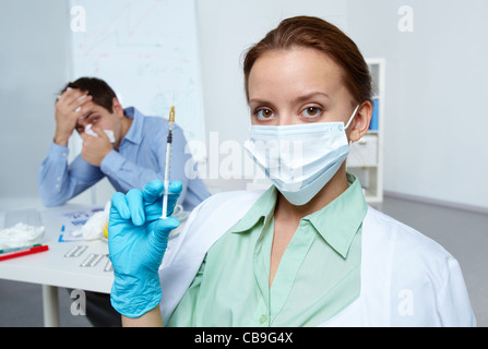 Bild der Geschäftsmann Niesen mit Krankenschwester Holding Spritze auf Hintergrund Stockfoto