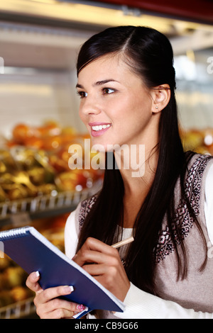 Bild hübsche Frau mit Notepad suchen irgendwo im Supermarkt Stockfoto