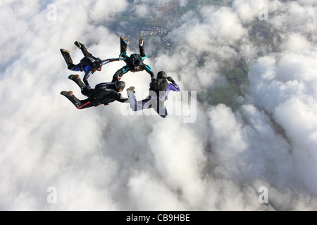 Vier Fallschirmspringer im freien Fall über eine Bank von Wolken Stockfoto
